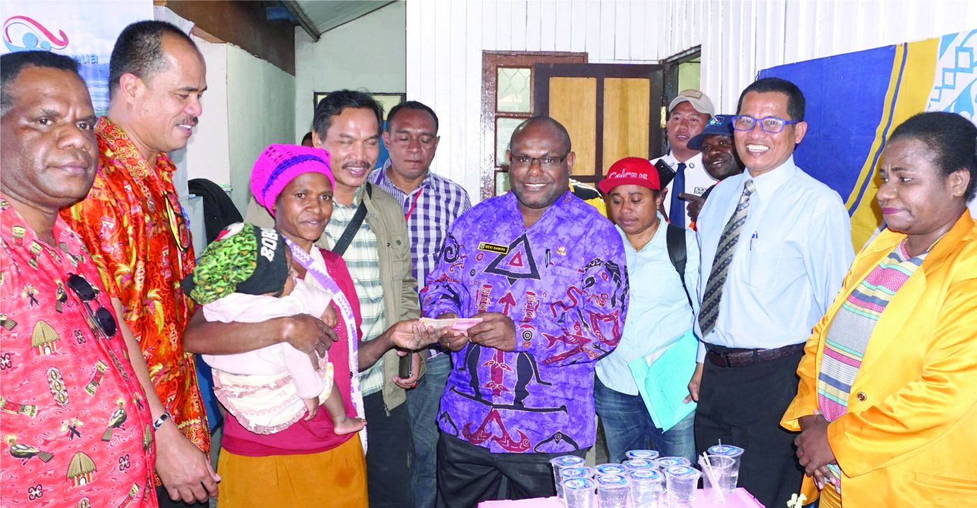 Meki Nawipa secara simbolis memberikan dana bantuan  BANGGA Papua kepada salah satu ibu penerima  manfaat 