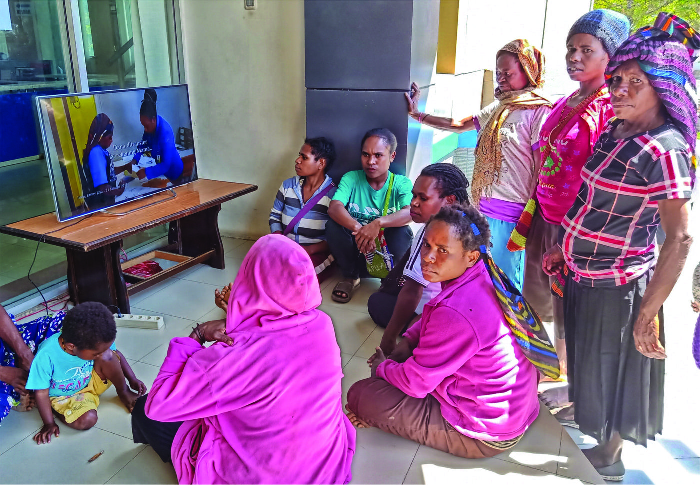   Nicodemus Wanma (kiri) Para ibu penerima manfaat  menyaksikan video sosialisasi pembayaran dan pemanfaatan  dana BANGGA Papua (kanan).  Foto : Syaifullah/Yayasan BaKTI