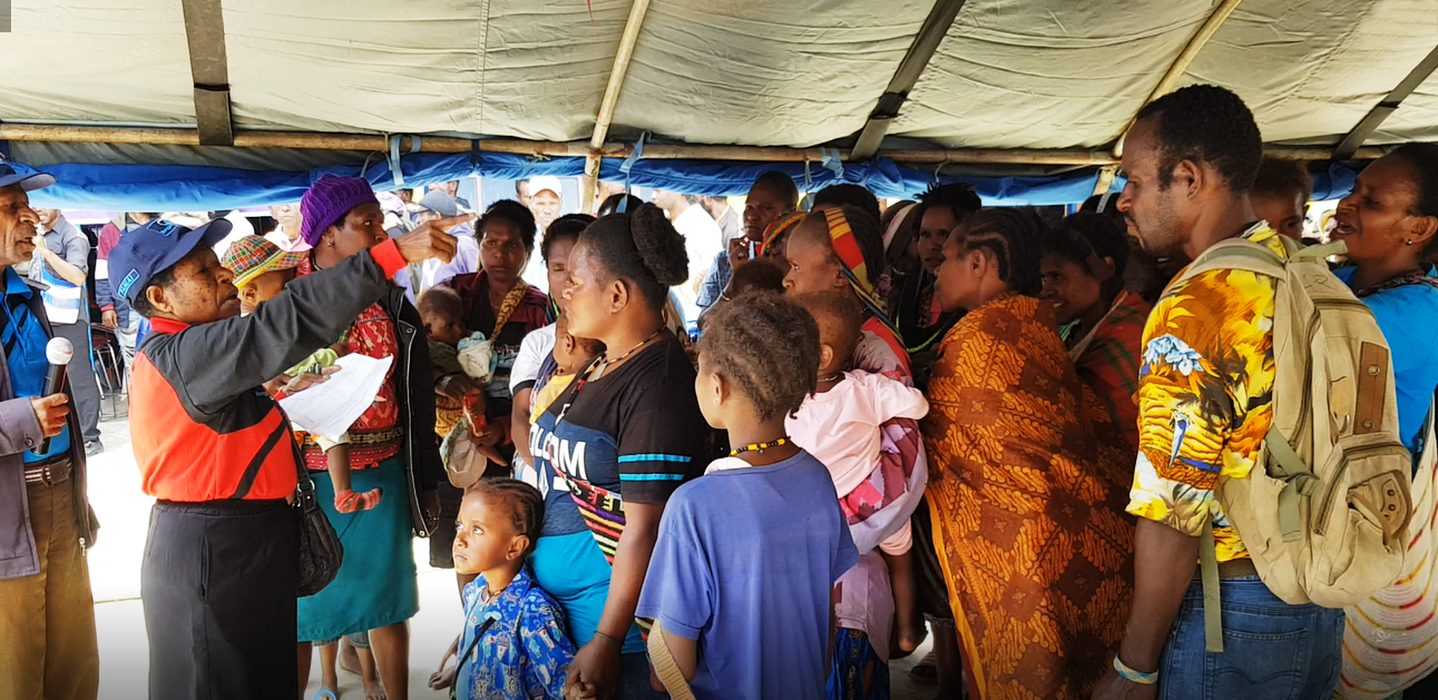 Mama Emi mengatur ibu-ibu dari Distrik Bibida yang sedang antri menerima pembayaran dana BANGGA Papua. Sosialisasi yang dilakukan mama Emi telah membuat mereka paham tentang bagaimana menggunakan dana tersebut.