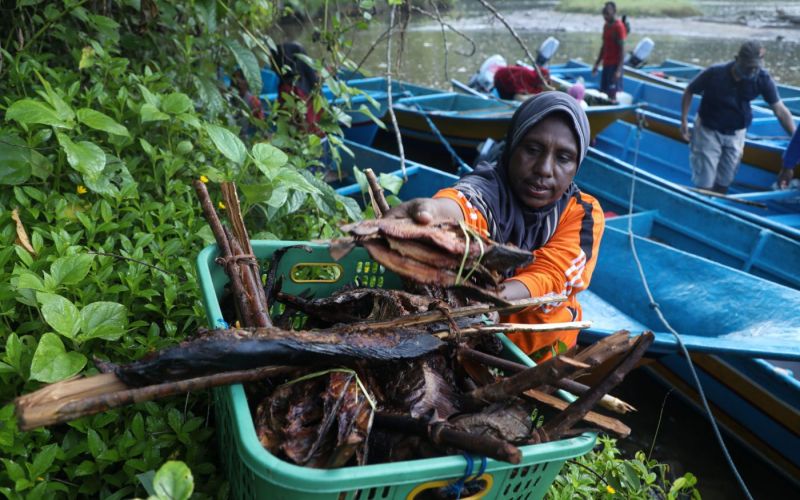 Warga menurunkan ikan asap dari perahu untuk dijual di Pasar Mambunibuni di Distrik Kokas, Kabupaten Fakfak, Papua Barat. KOMPAS/HERU SRI KUMORO