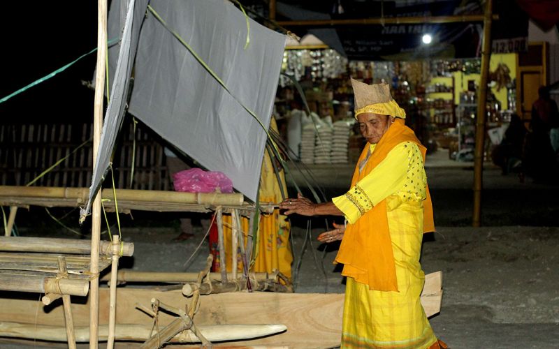 Nabiyah selaku sinsioan membacakan gane-gane berisi mantera dan doa kepada perahu yang hendak dilarung dalam Upacara Adat Masoro. (Foto: Mughni Mayah/Tutura.Id)