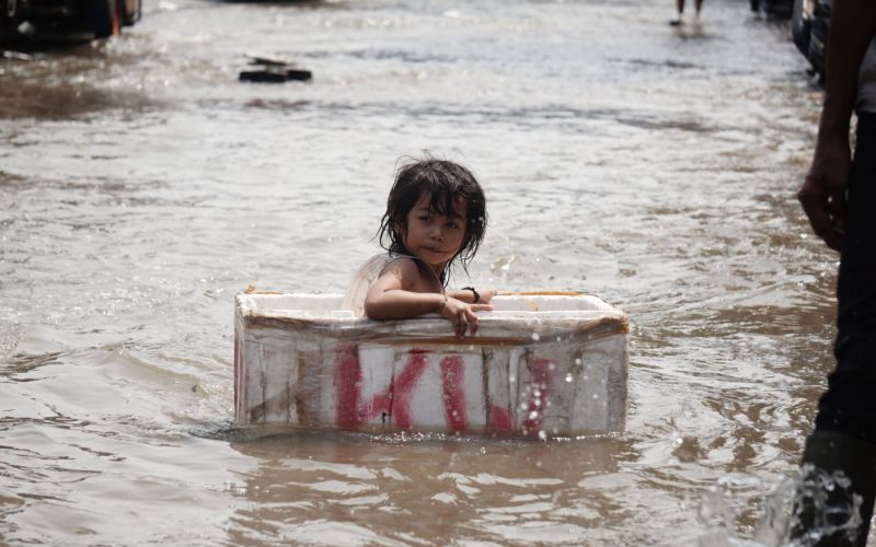 Seorang anak bermain di kawasan yang terendam banjir di Jakarta Utara, pada November 2020. Foto : shutterstock/mongabay.co.id